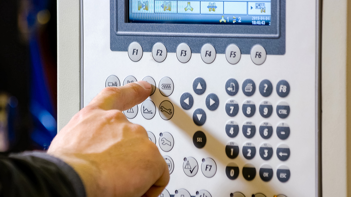 A hand pressing buttons on a control panel.