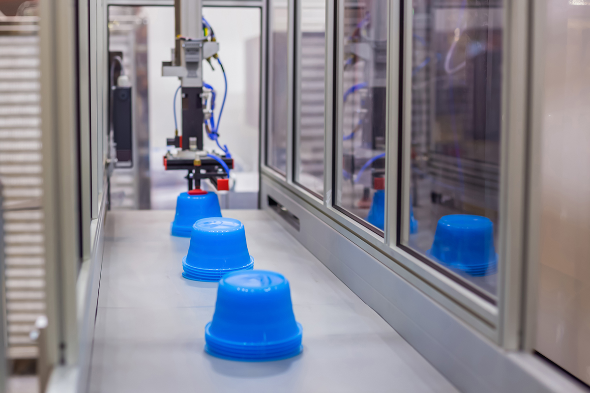 Plastic containers on a conveyor belt on an automatic injection molding machine.